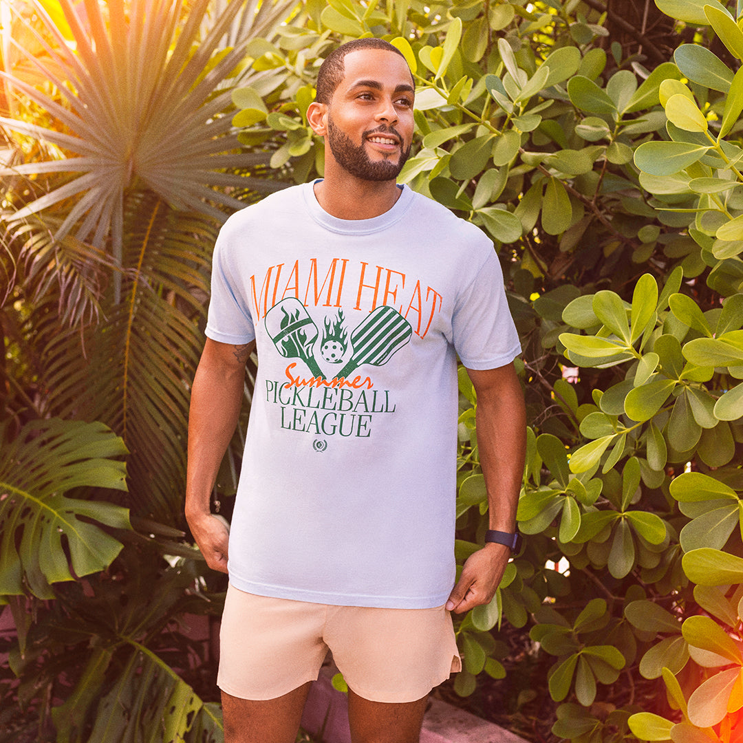 White unisex tee with Miami HEAT logo and Pickleball League graphic, worn outdoors. - Court Culture HEAT Pickleball League Unisex Tee