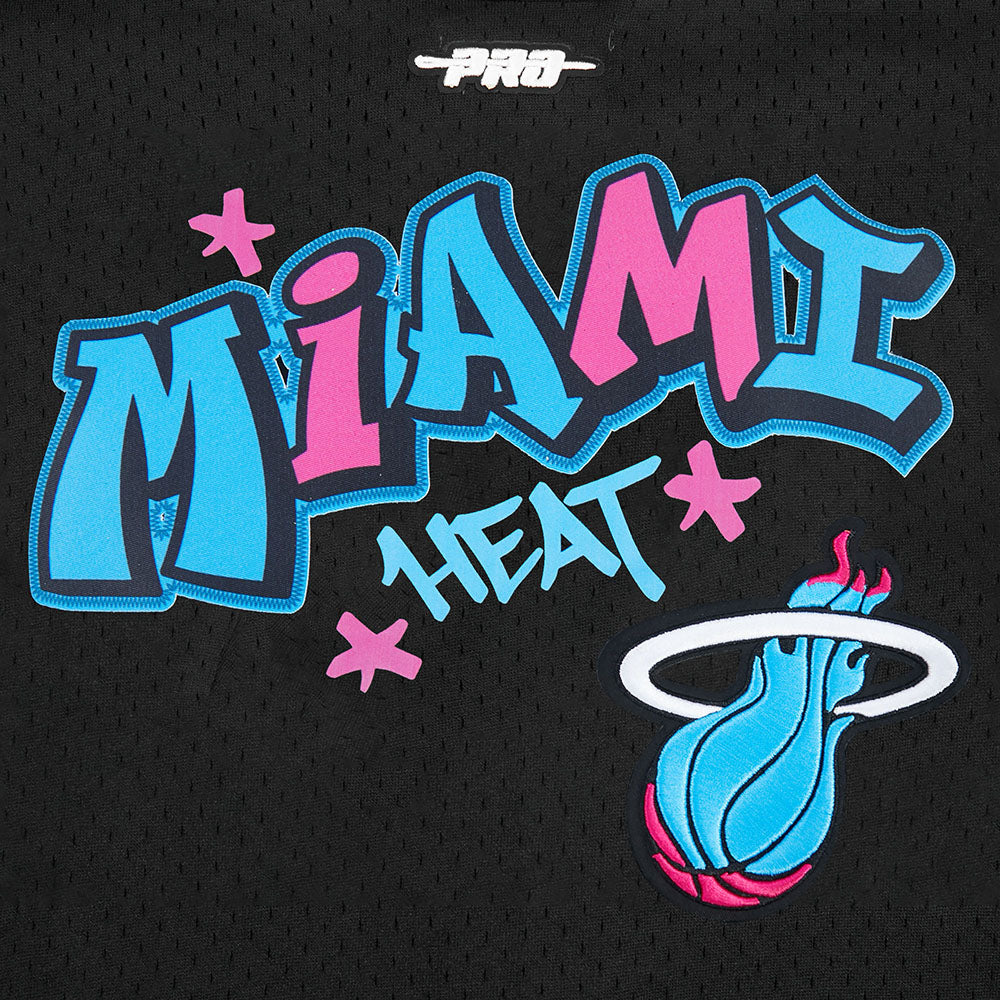 The Pro Standard Miami HEAT Original Vice Nights Youth Mesh Shirt features a colorful graffiti-style logo with pink and blue letters, stars, and a flaming basketball on black polyester for a standard fit and easy machine wash care.