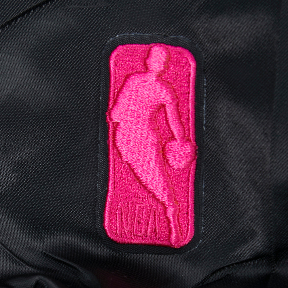 A close-up of the pink embroidered NBA logo on the black polyester Pro Standard Miami HEAT Original Vice Nights Youth Satin Jacket, featuring standard fit and machine washable design.