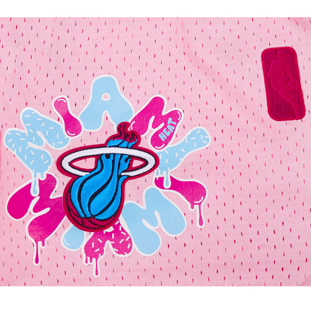 A close-up of Pro Standard Miami HEAT Original Vice Nights Girls Graffiti Shorts, made of pink polyester with a relaxed fit, featuring blue and pink Miami Heat graffiti-style logo and a small red NBA patch on the right.