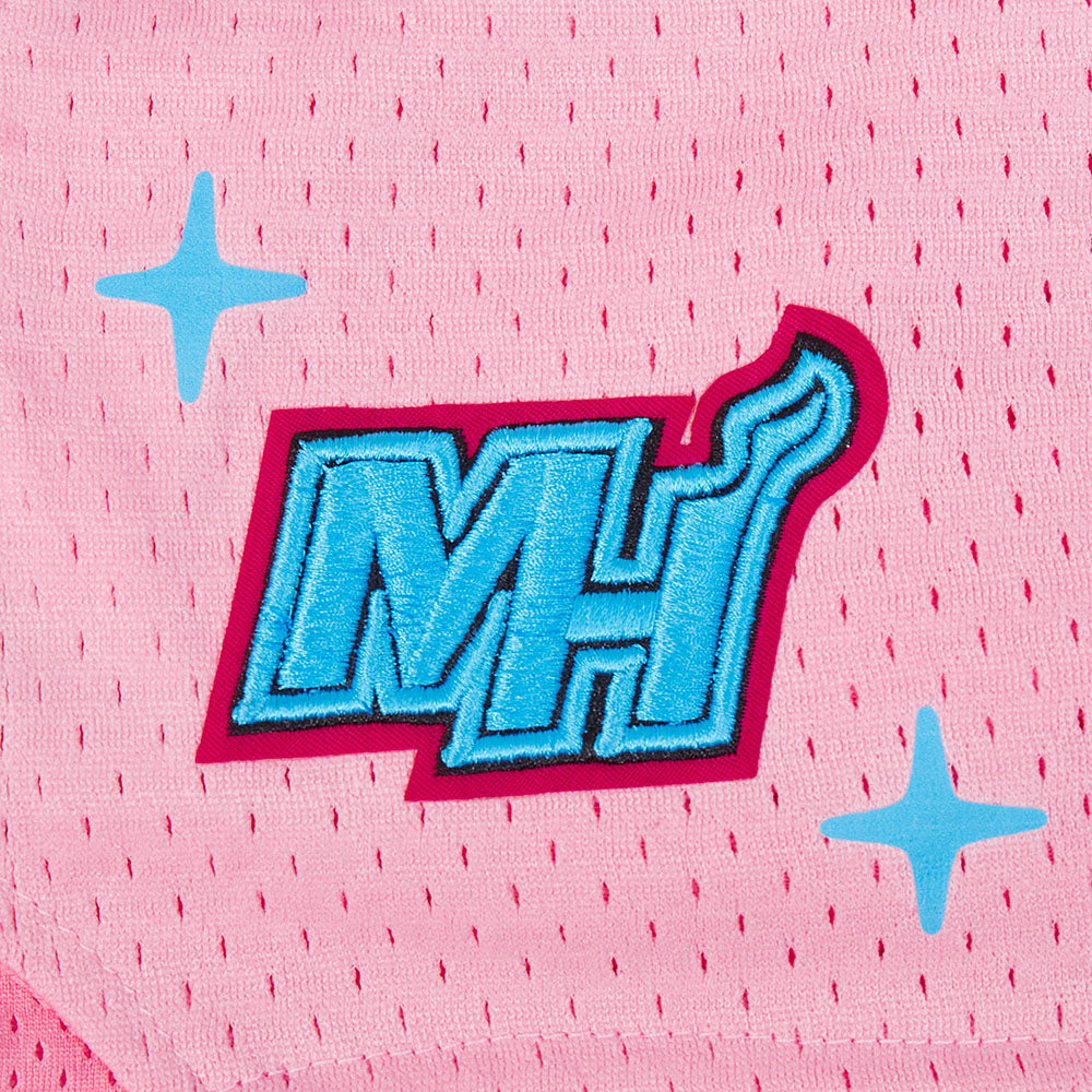 Close-up of Pro Standard Miami HEAT Original Vice Nights Girls Graffiti Shorts in pink polyester mesh, showcasing a blue and white MH logo with red outline, stylized flame, and two blue star graphics.