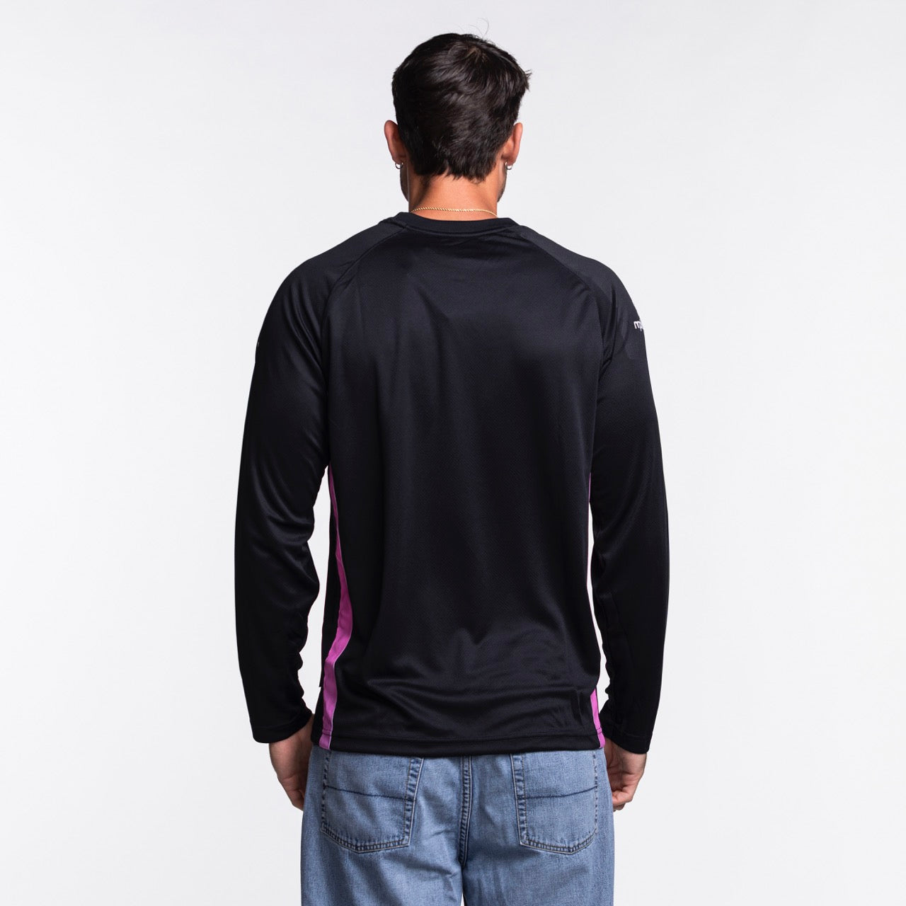 A person with short dark hair, seen from behind in blue jeans, is wearing a Nike Miami HEAT Original Vice Nights Shooting Shirt by Nike, standing against a plain white background.