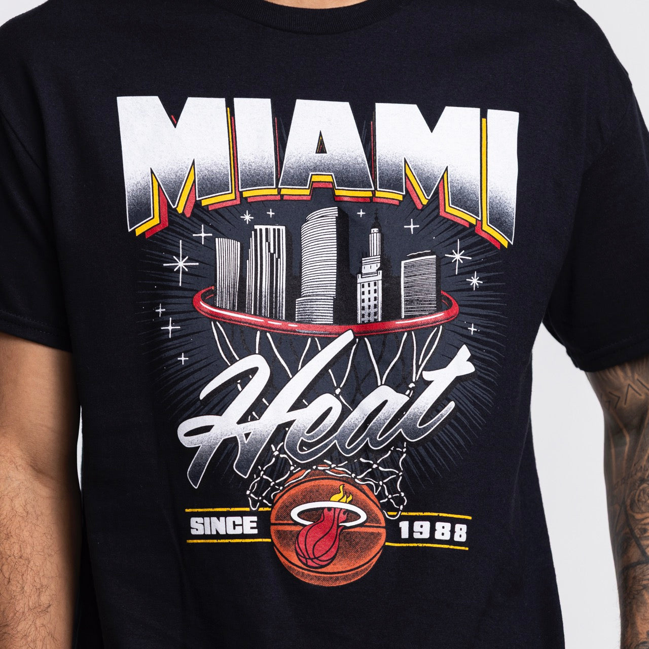 A person wears the Miami HEAT Retro Net Tee by Item Of The Game, a black standard-fit shirt with 