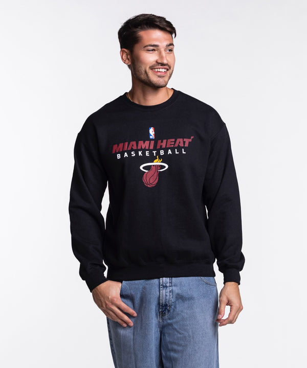 A man smiles in an Item Of The Game Miami HEAT NBA Basketball Crewneck, crafted from soft cotton-polyester, paired with blue jeans against a plain white background.