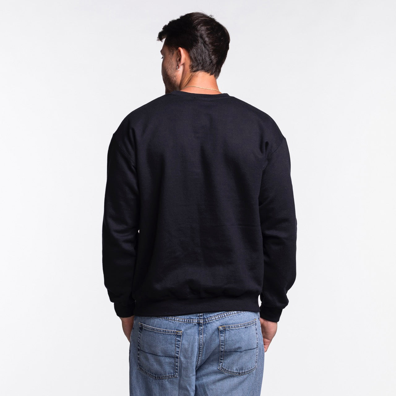 A man faces away from the camera, wearing the Miami HEAT NBA Basketball Crewneck by Item Of The Game and blue jeans in a standard fit against a plain white background.