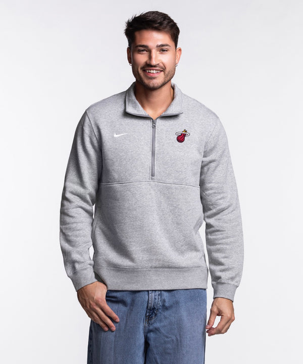 A man smiles in a Nike Miami HEAT Fleece 1/2 Zip Jacket and blue jeans, standing against a plain white background.