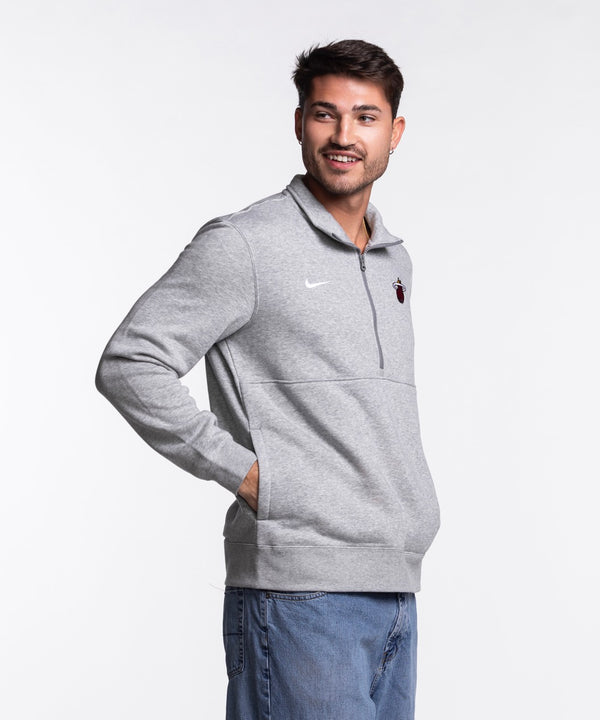 A man smiles in a Nike Miami HEAT Fleece 1/2 Zip Jacket and blue jeans, standing against a plain white background.