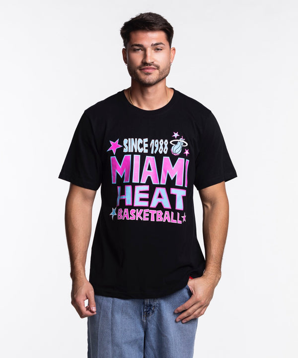 A man faces forward in the Sportiqe Miami HEAT Original Vice Nights Star Tee—a black, 100% cotton, standard-fit t-shirt with colorful text and stars—paired with light blue jeans against a plain white background.