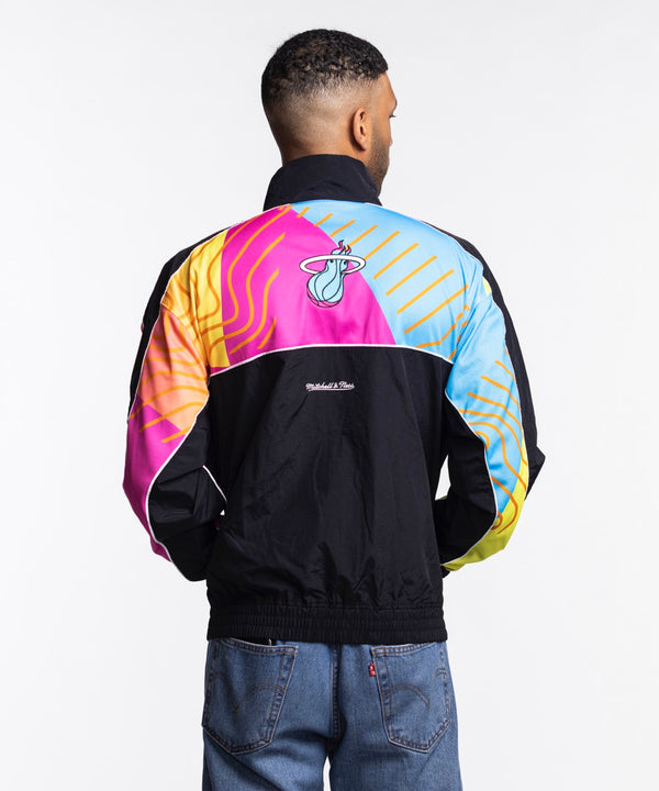 A man stands against a white background, looking left with his hands at his sides, wearing the Court Culture x Mitchell & Ness Original Vice Nights 