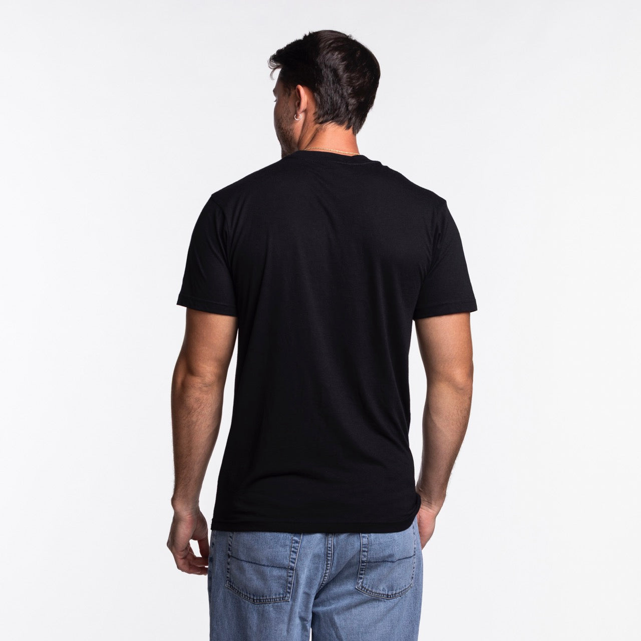 A man stands with his back to the camera, wearing a Sportiqe Miami HEAT NBA Tee by Sportiqe in a standard fit and light blue jeans, set against a white background.