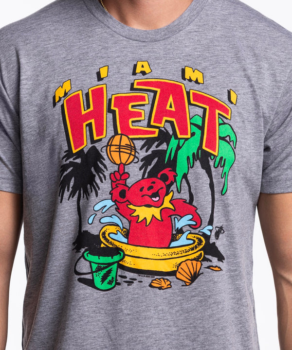 A man stands facing forward in blue jeans, wearing the Homage Miami HEAT Grateful Dead Bear Tee by Homage—a comfortable standard fit T-shirt made from polyester, cotton, and rayon that’s easy to machine wash cold.