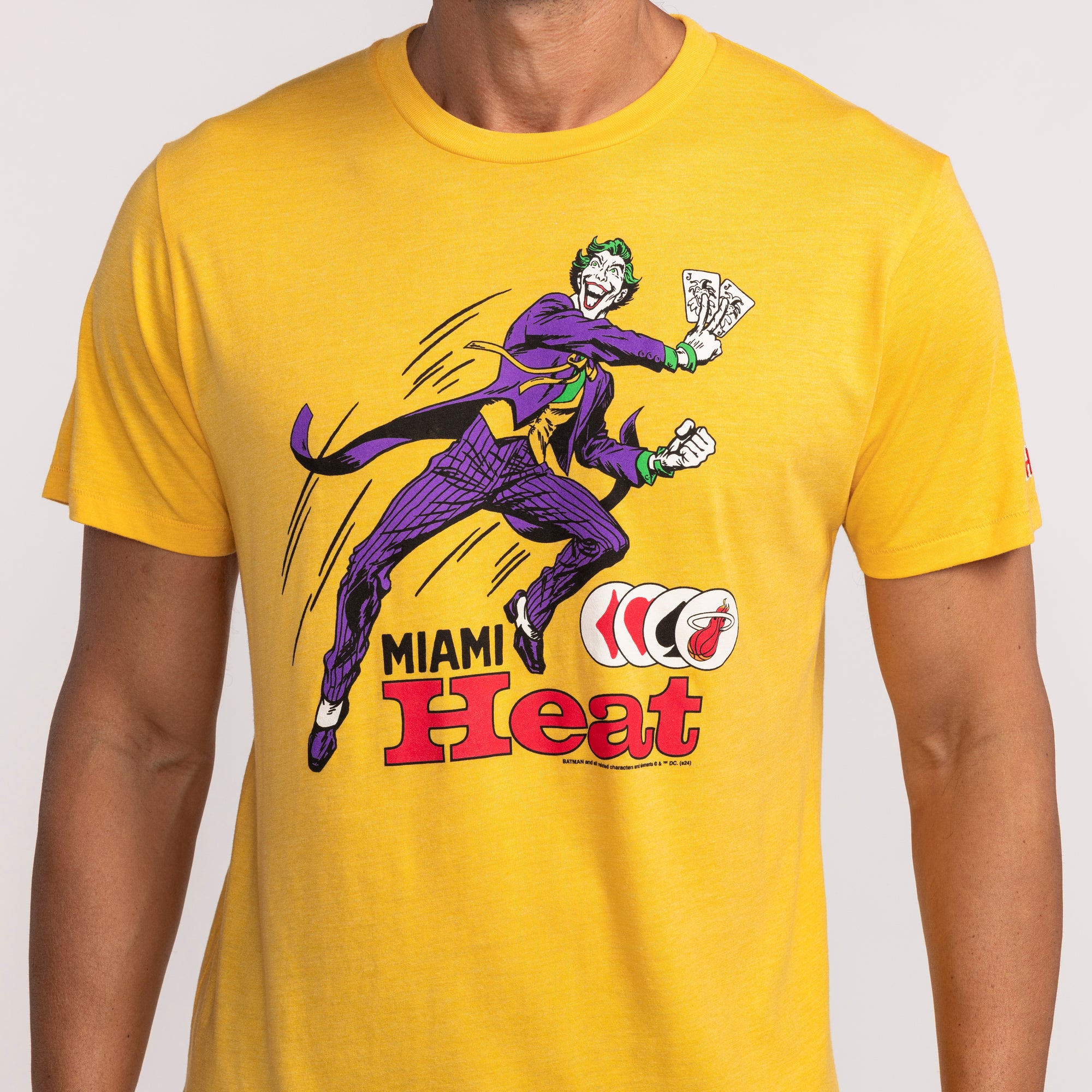 Yellow Homage Miami HEAT Joker graphic tee with purple and green comic character design. - Homage Miami HEAT Joker Tee