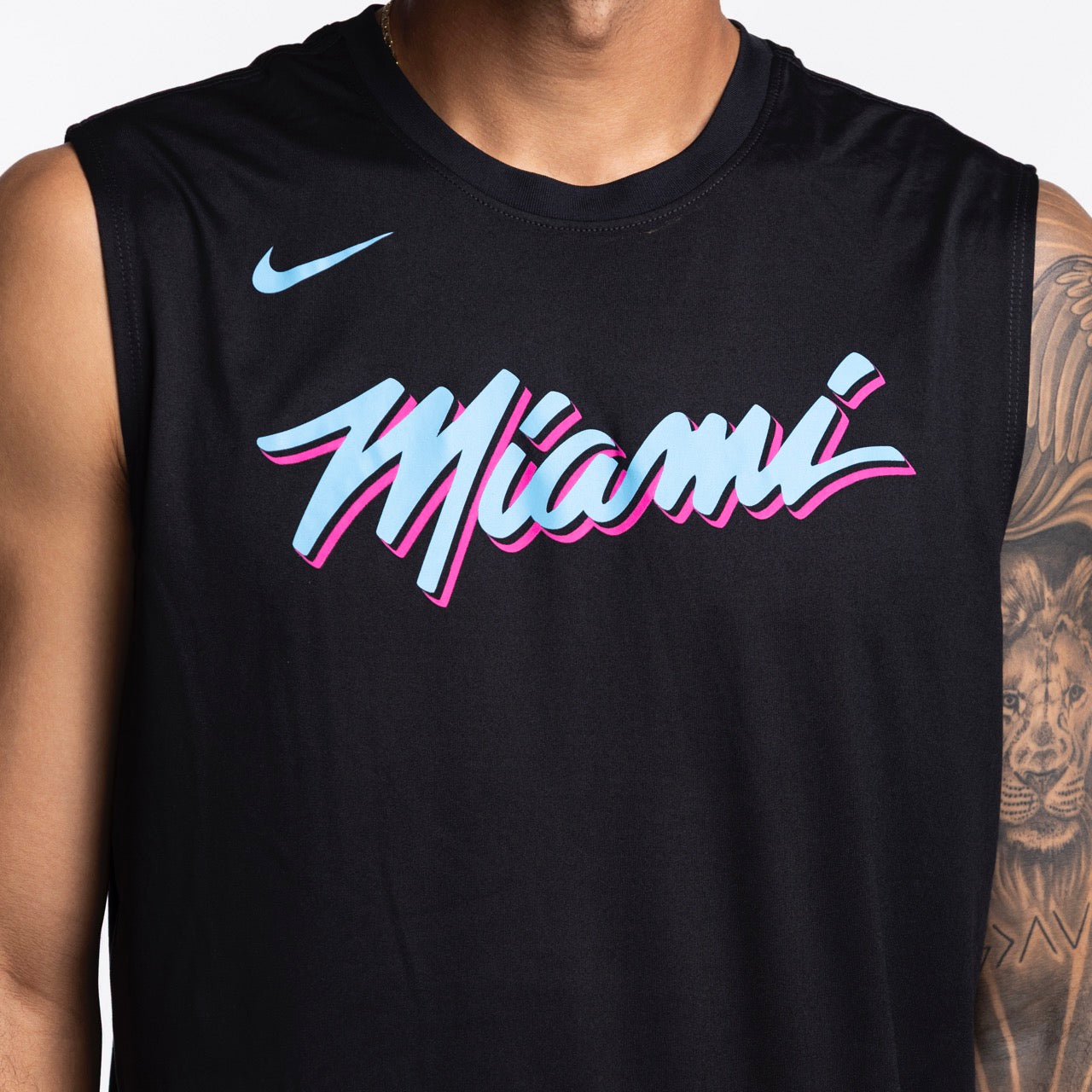 A person wears a Nike Miami HEAT Original Vice Nights Sleeveless Tee—black, with 