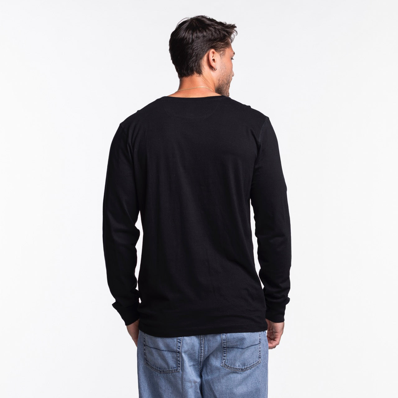 A man faces away from the camera wearing a Sportiqe Miami HEAT Original Vice Nights Long Sleeve Tee and light blue jeans, set against a plain white background.