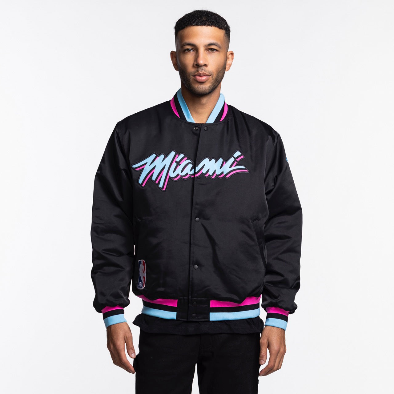 A man wears the Nike Miami HEAT Original Vice Nights Bomber Jacket, a black polyester jacket with 