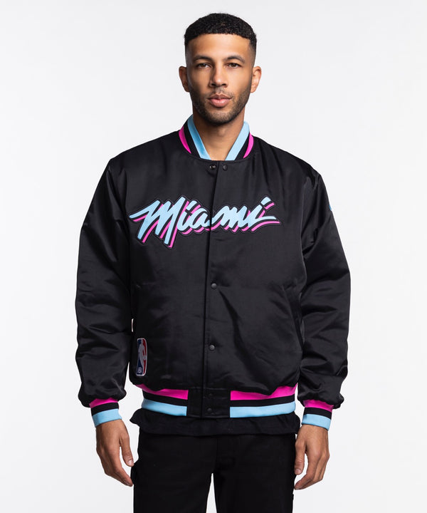 A man wears the Nike Miami HEAT Original Vice Nights Bomber Jacket, a black polyester jacket with 