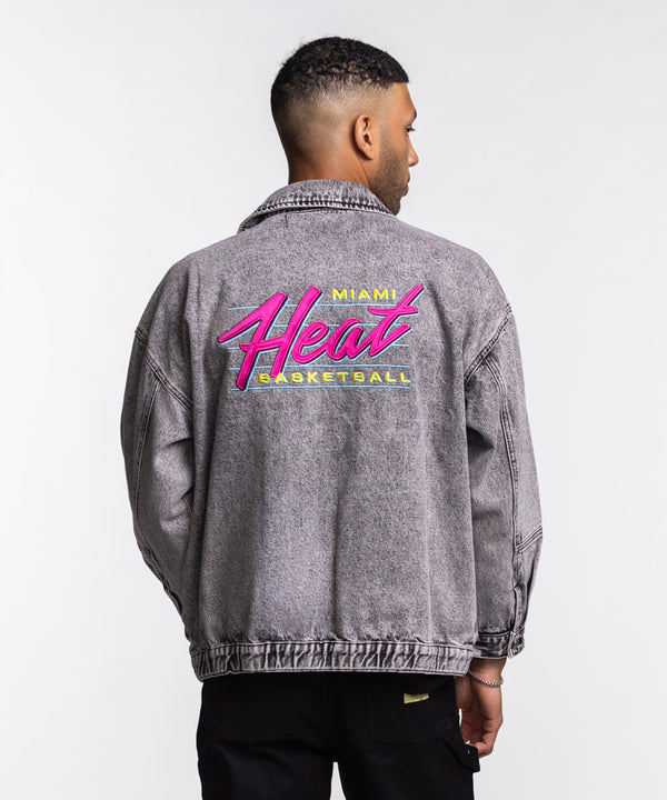 A young woman with long brown hair wears the Court Culture X The Wild Collective Original Vice Nights Denim Patch Unisex Jacket over a white shirt and black pants, standing against a plain light background.