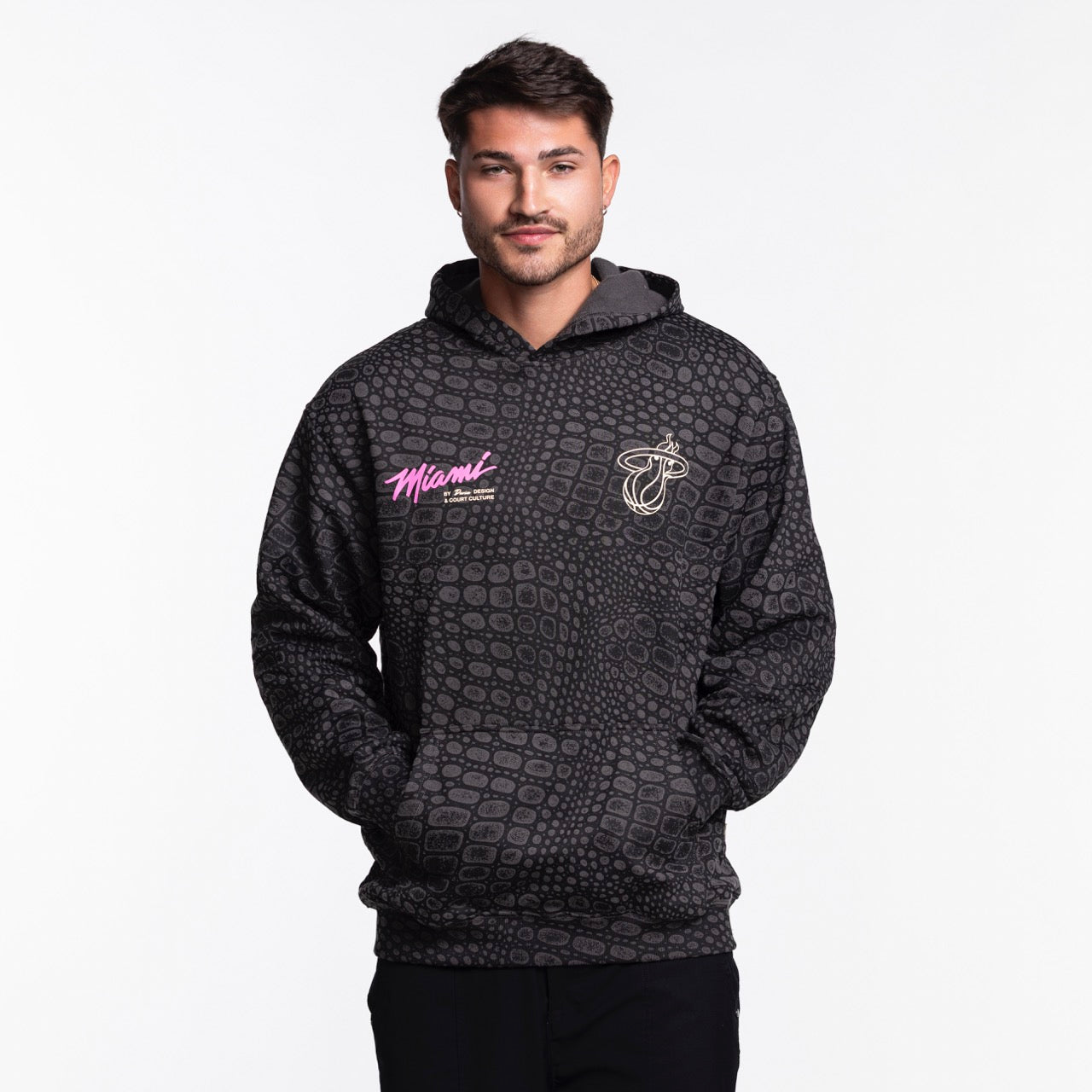 A man wears the Court Culture x Duvin Original Vice Hoodie—a black, geometric-patterned hoodie with 