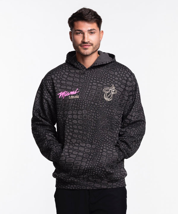 A man wears the Court Culture x Duvin Original Vice Hoodie—a black, geometric-patterned hoodie with 