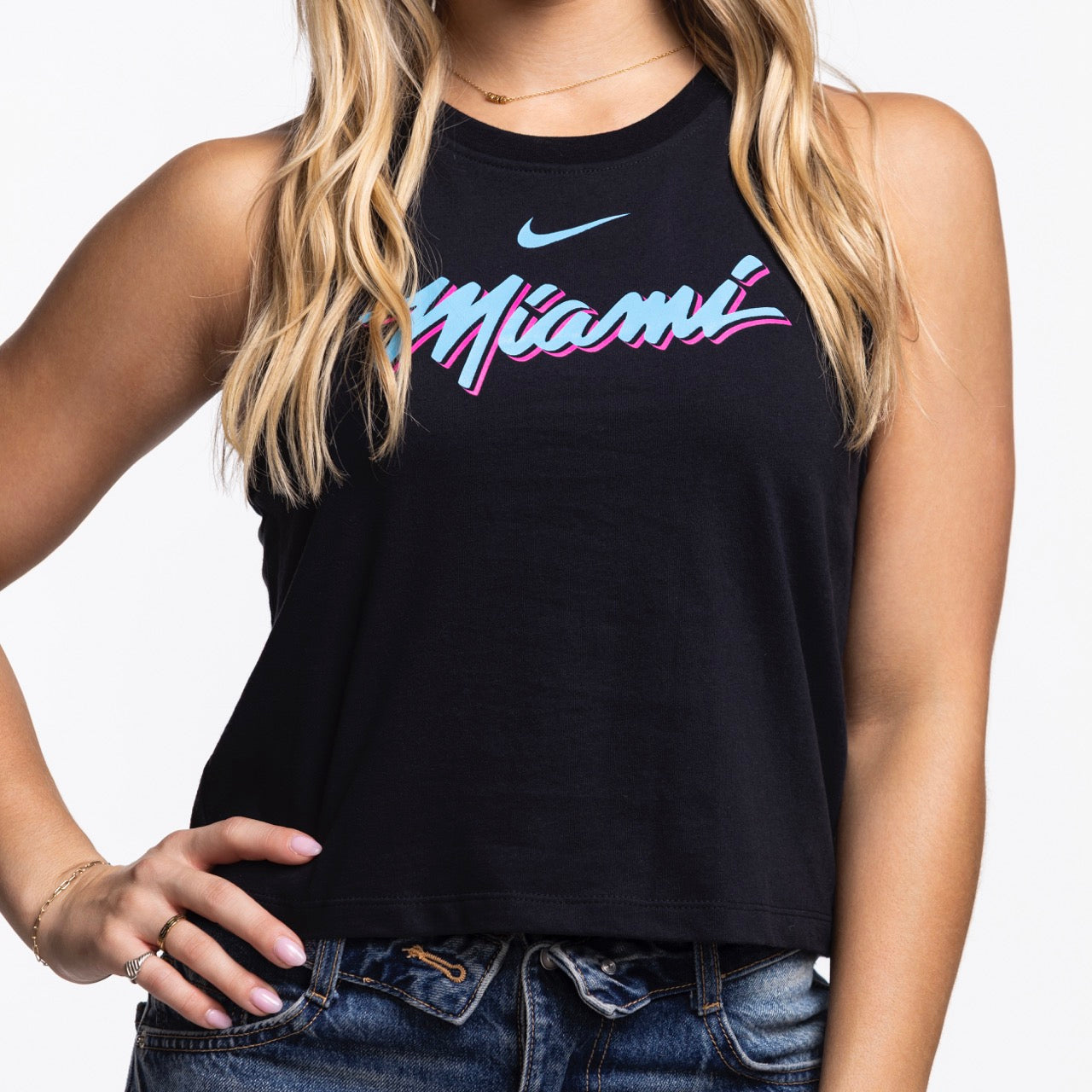 A woman wears the Nike Miami HEAT Original Vice Nights Cropped Women's Tank—a black sleeveless top with colorful 