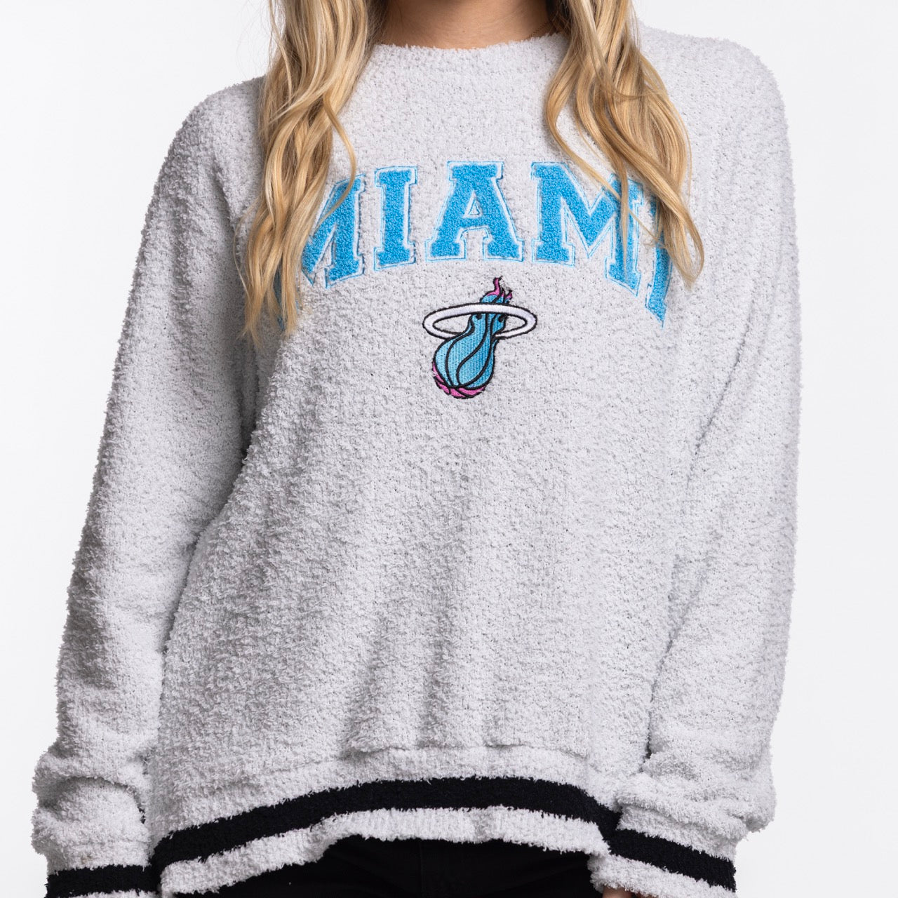 A person wears the Concepts Sports Miami HEAT Original Vice Nights Women's Crewneck—an oversized, fuzzy light gray sweater with 