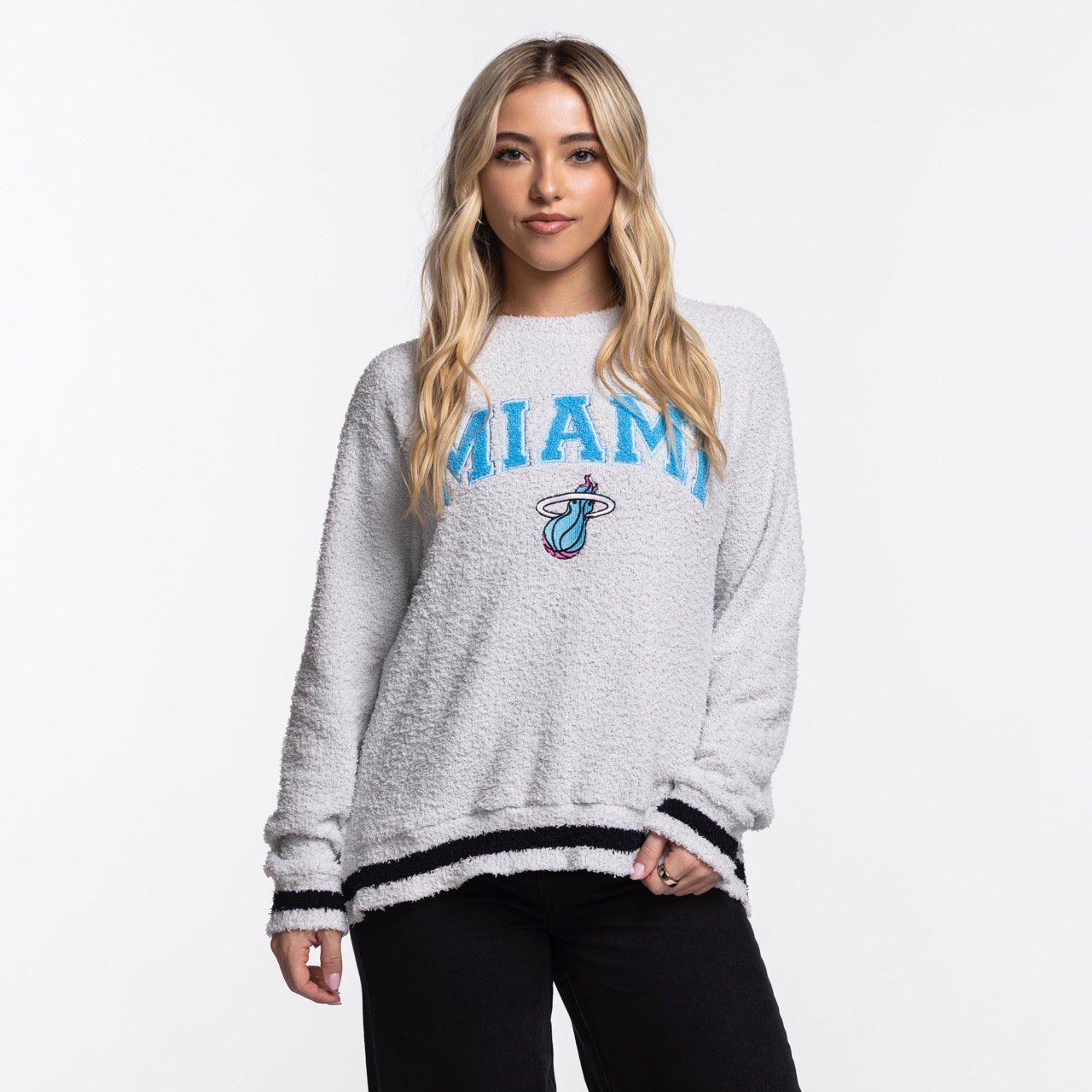 A woman with long, blonde hair wears the Concepts Sports Miami HEAT Original Vice Nights Women's Crewneck—an oversized, 100% cotton light gray sweatshirt with 