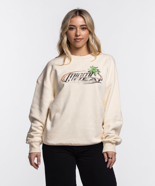 A woman with long blonde hair wears a cream Court Culture x Duvin Sun Crew Sweater and black pants, standing against a plain white background.