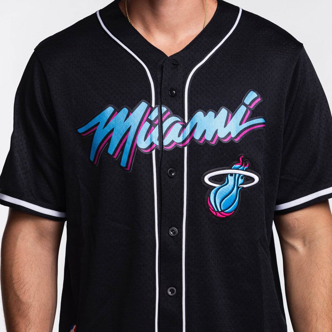 A person wears the Pro Standard Miami HEAT Original Vice Nights Baseball Jersey, a black polyester, standard-fit top with 