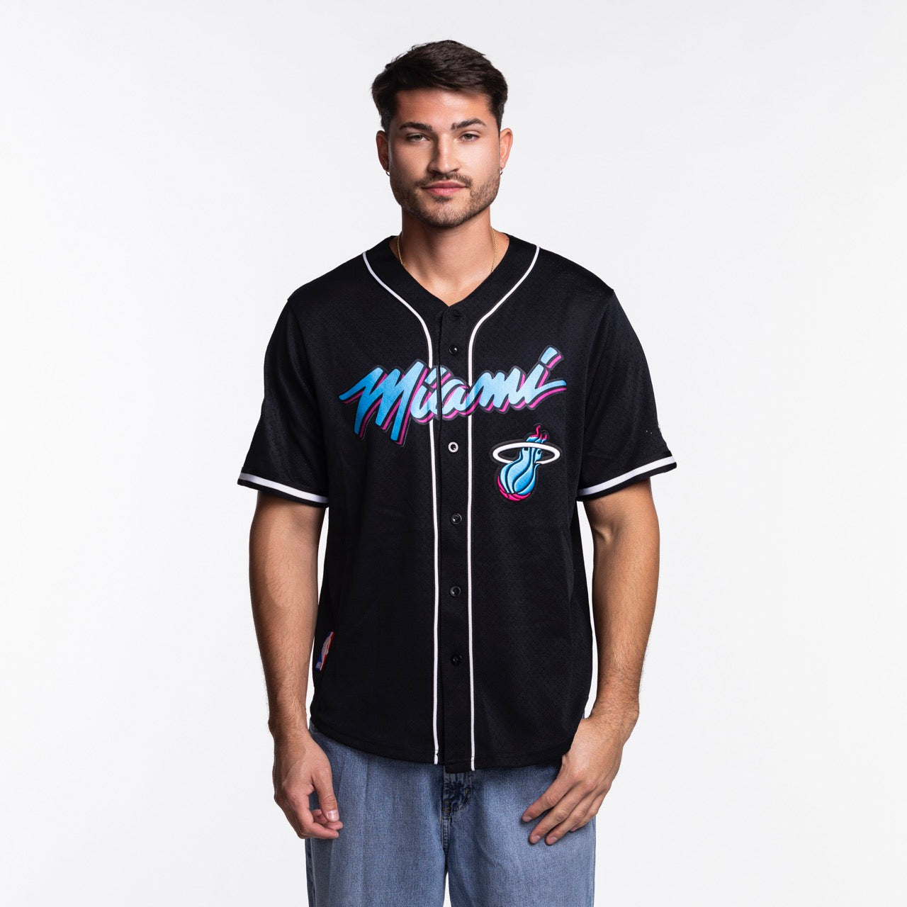 A man wearing the Pro Standard Miami HEAT Original Vice Nights Baseball Jersey, featuring colorful Miami text and team logo on the front, stands against a plain white background.