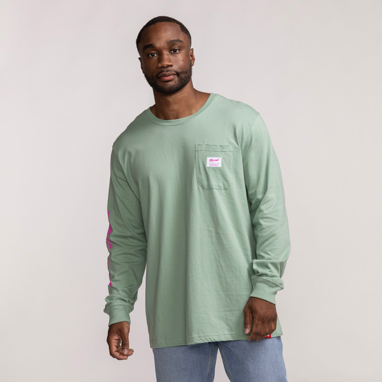 Men's long sleeve tee in sage green with Miami HEAT logo patch on chest and pink wordmark down sleeves. - Sportiqe Miami HEAT Original Vice Wordmark Long Sleeve Tee