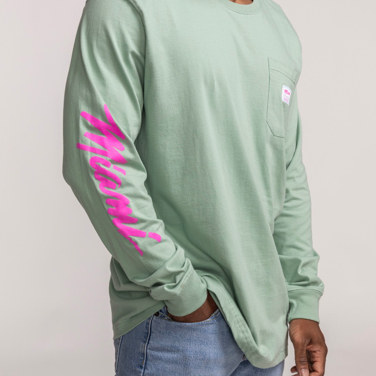 Sage green long sleeve tee with bright pink Miami HEAT wordmark on sleeve and chest pocket. - Sportiqe Miami HEAT Original Vice Wordmark Long Sleeve Tee