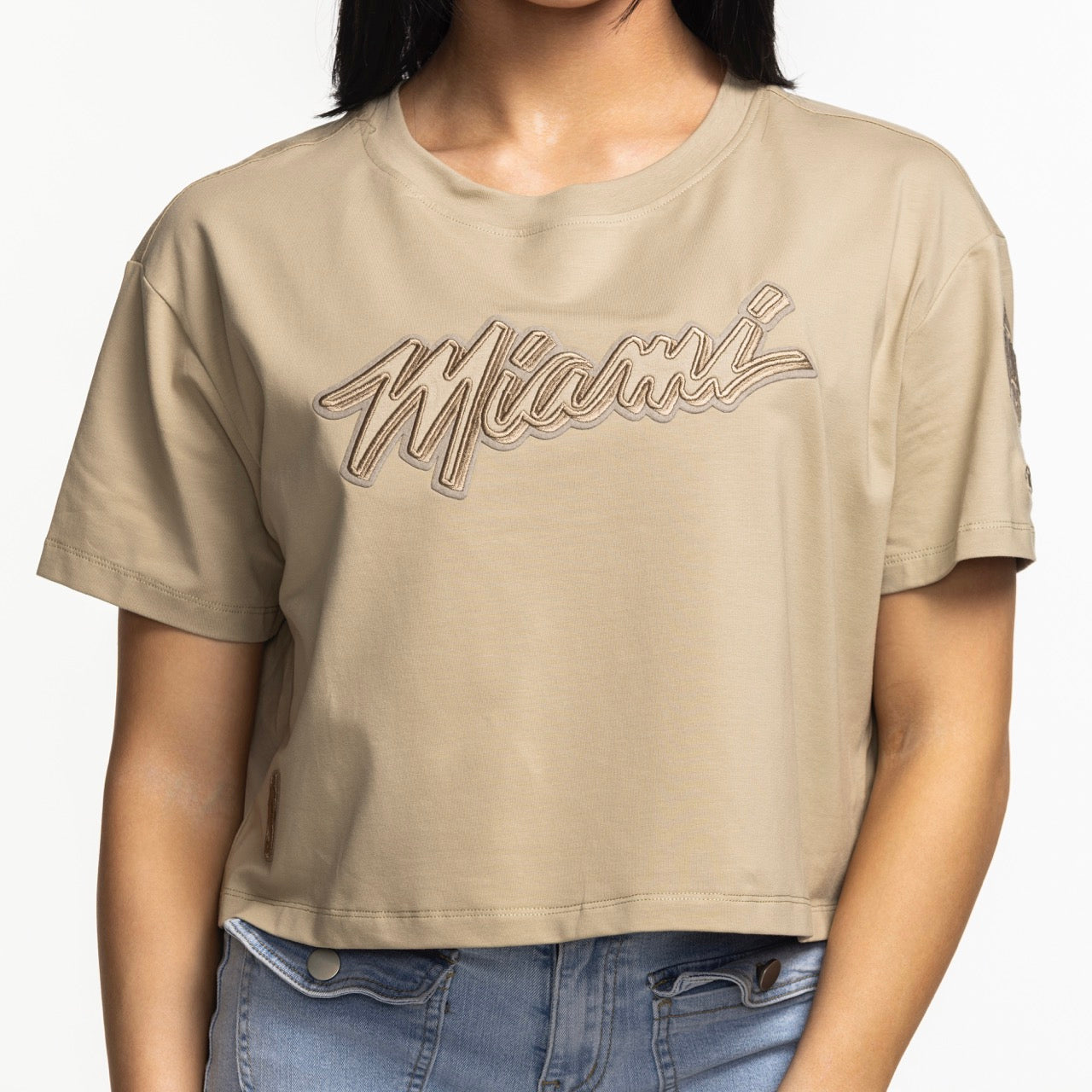 A woman wears the Pro Standard Miami HEAT Original Vice Nights Beige Women's Boxy Tee, featuring 