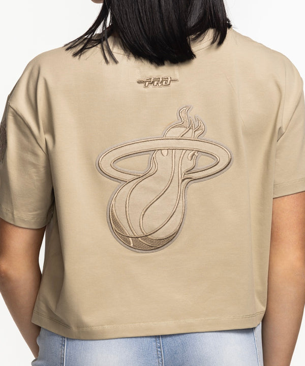 A woman with straight dark hair smiles while wearing the Pro Standard Miami HEAT Original Vice Nights Beige Women's Boxy Tee and light blue jeans, standing against a plain white background.