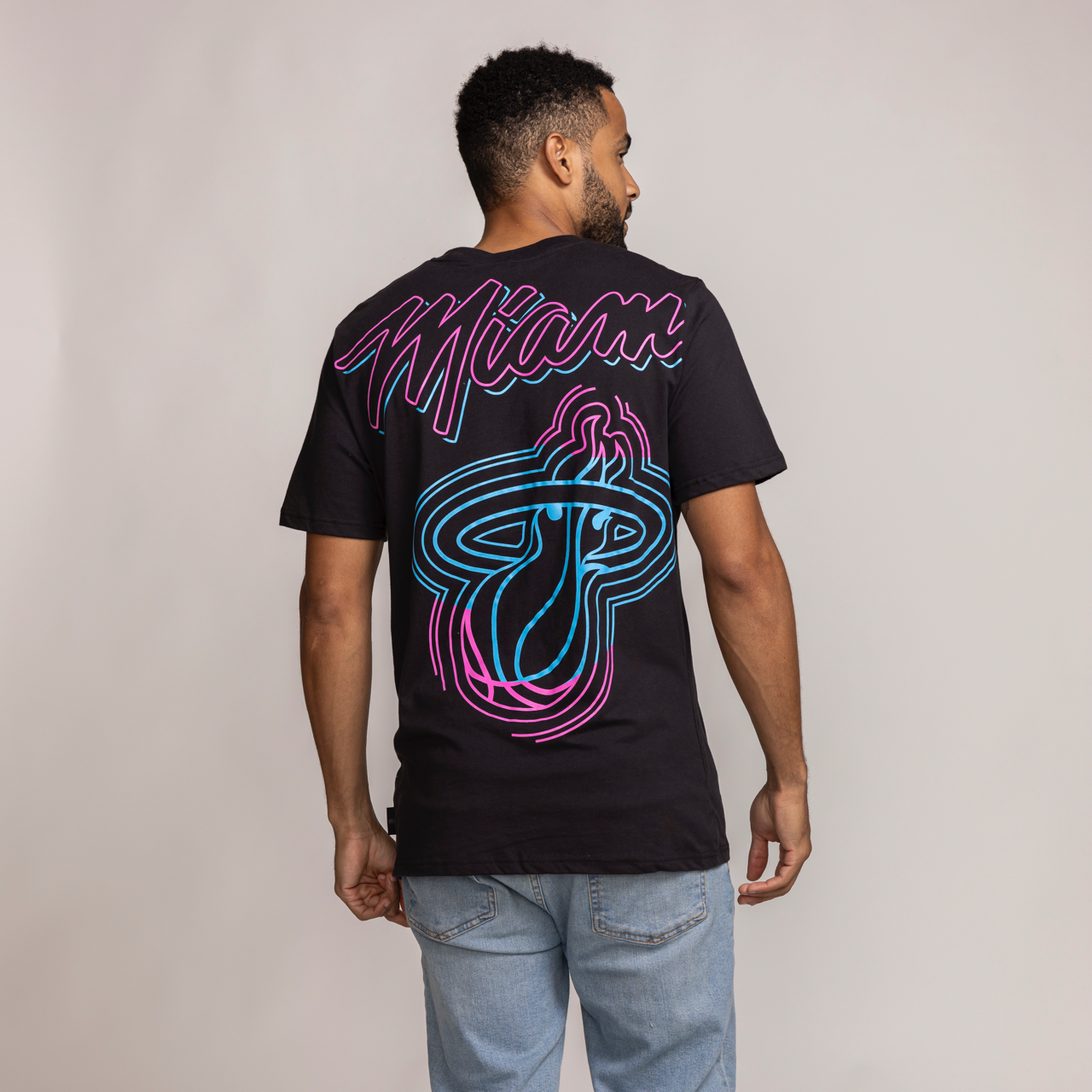 Black Miami HEAT Original Vice Venue tee with pink and blue graphic logo on back, worn by male model. - Stadium Essentials Miami HEAT Original Vice Venue Tee