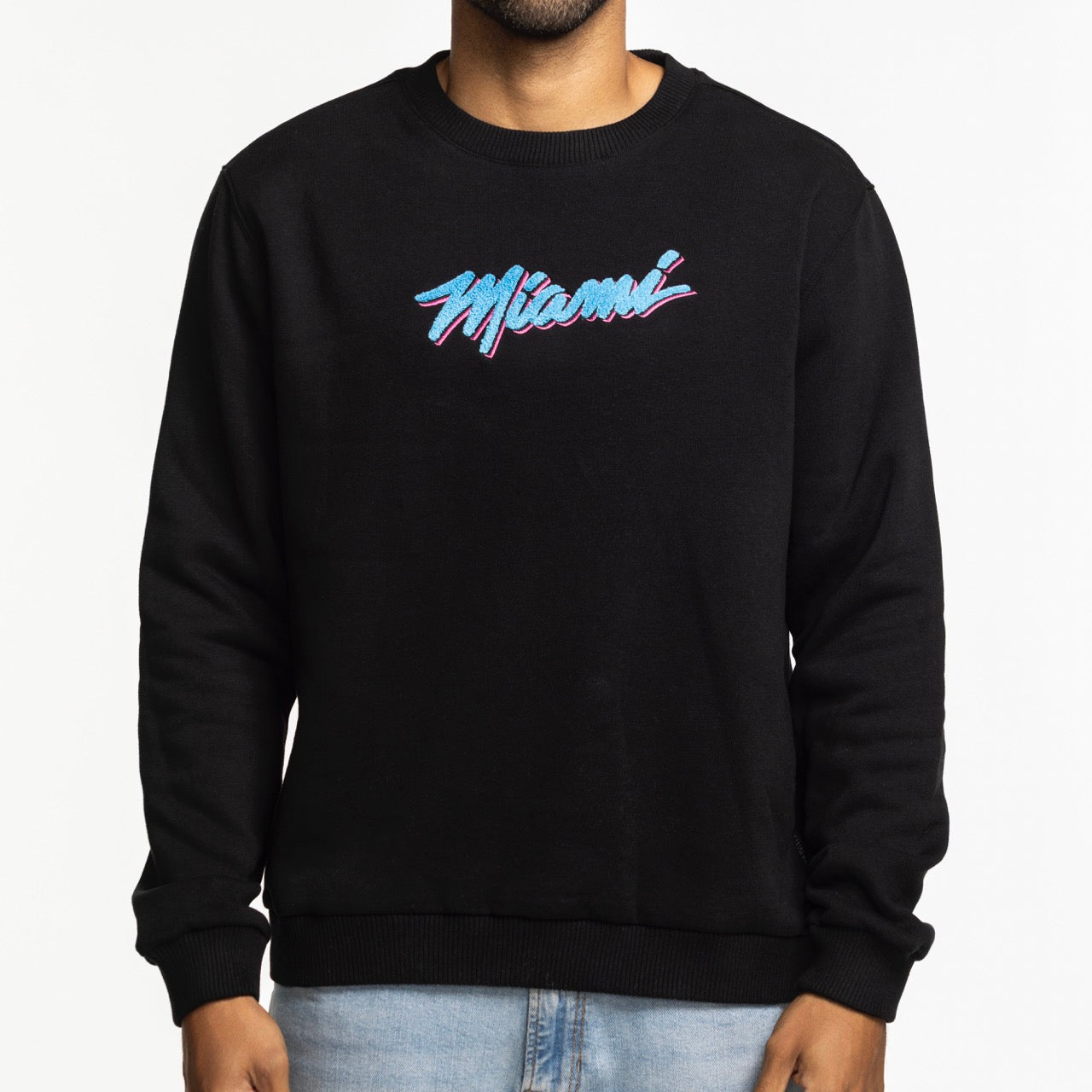 A person wearing the Stadium Essentials Miami HEAT Original Vice Nights Club Level Crewneck, a black, standard-fit sweatshirt with 