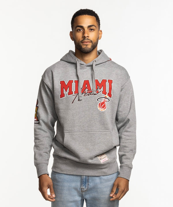 A man faces forward wearing the Mitchell & Ness Miami HEAT 2013 Champions Hoodie, featuring 