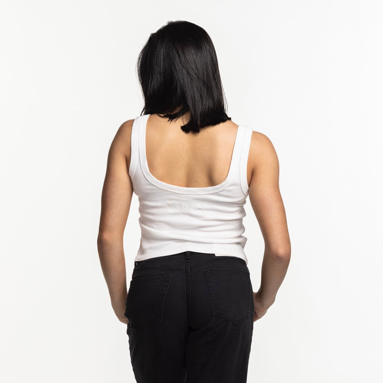 A person with straight black hair faces away, wearing the Court Culture Embroidered Logo Tank by Court Culture against a plain white background.
