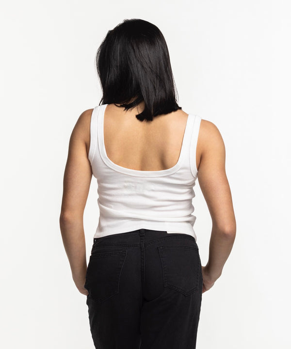 A smiling woman with straight dark hair wears the Court Culture Embroidered Logo Tank and black pants, standing against a plain white background.