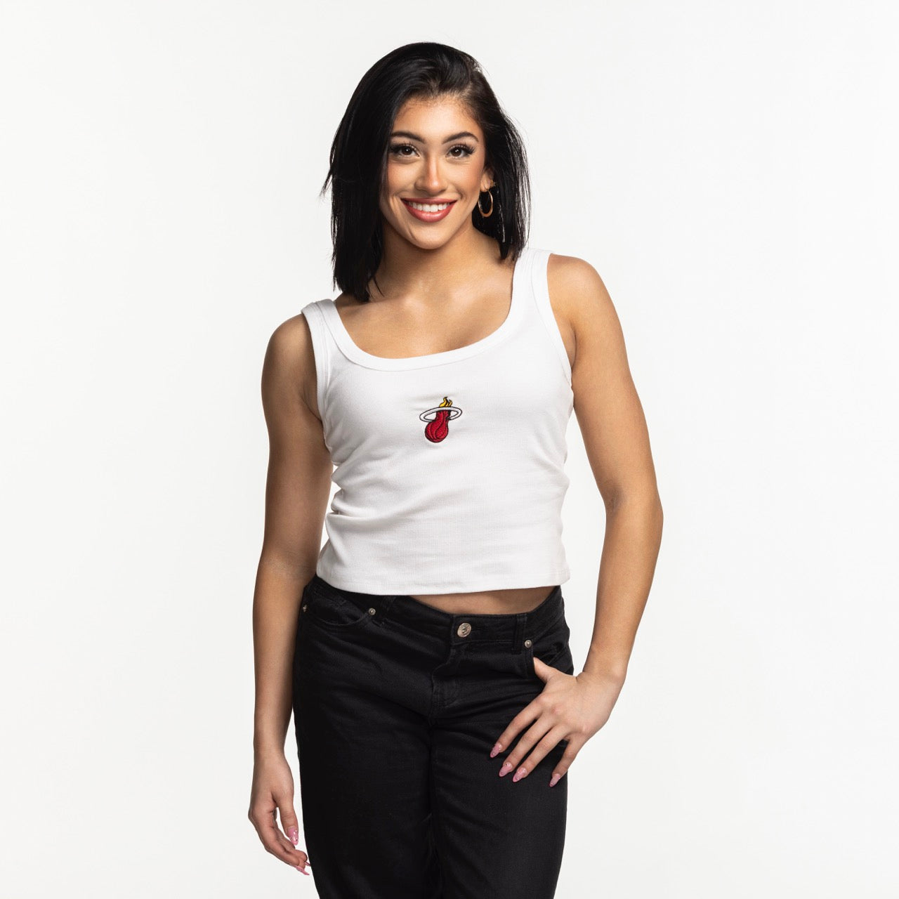 A smiling woman with straight dark hair wears the Court Culture Embroidered Logo Tank and black pants, standing against a plain white background.