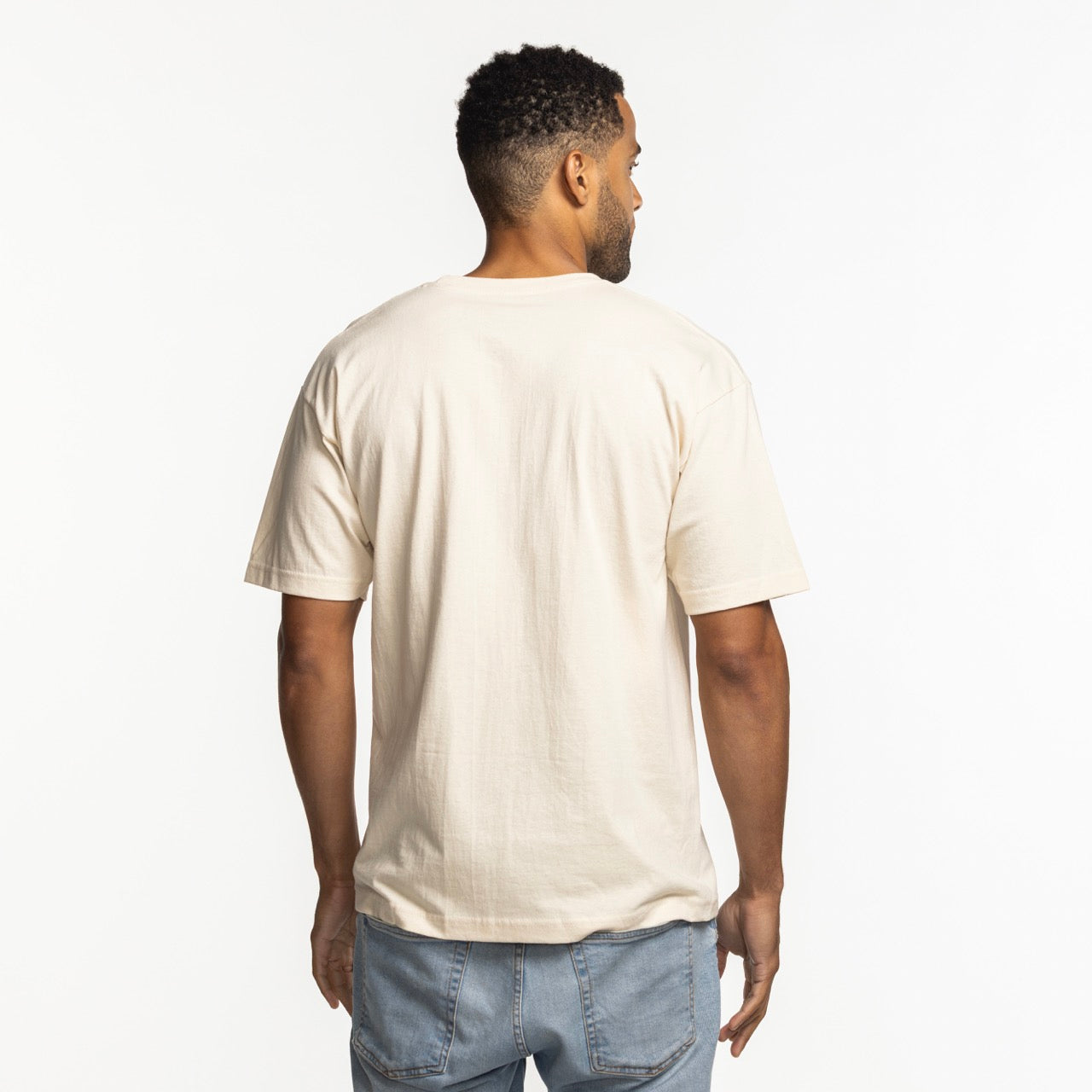 A man stands with his back to the camera, wearing a Mitchell & Ness Miami HEAT Sketched Out Tee and light blue jeans against a white background.