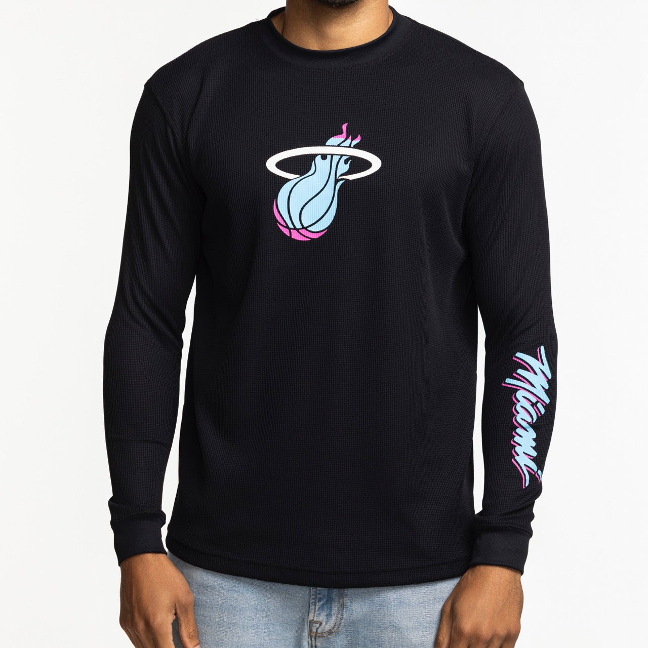 A person wears the Stadium Essentials Miami HEAT Original Vice Nights Long Sleeve Tee, featuring a blue and pink Miami Heat logo on black, 