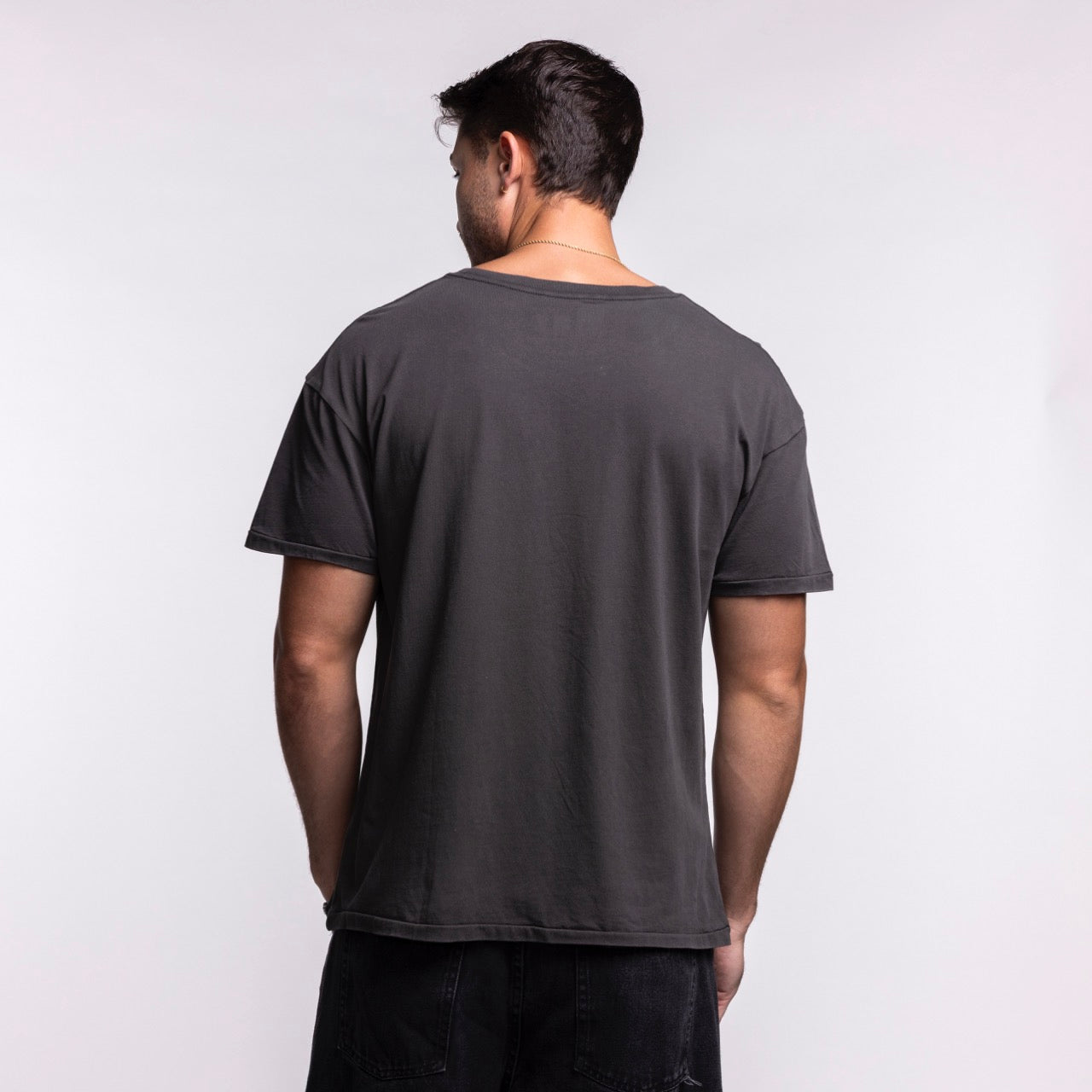 A man with short dark hair stands with his back to the camera, wearing the Court Culture 