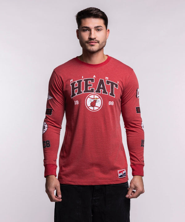 A man stands facing forward wearing the New Era Miami HEAT Red Cuffed Long Sleeve Tee, featuring a HEAT basketball logo and 
