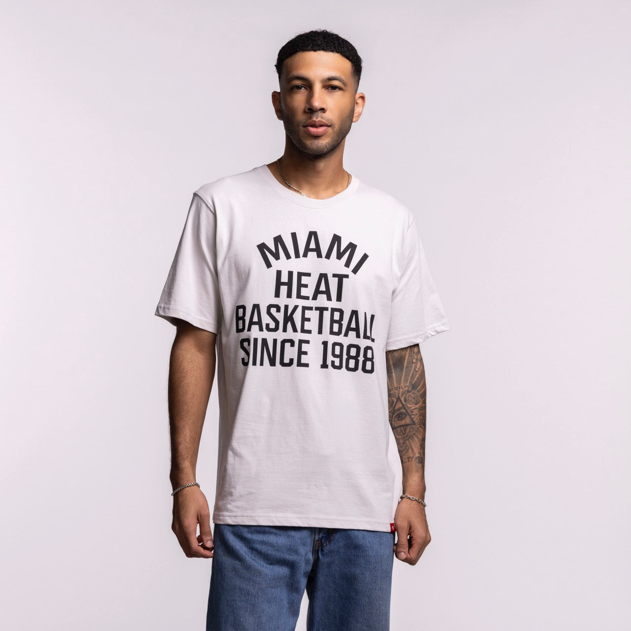 A man wearing the Sportiqe Miami HEAT 1988 Basketball Tee—white, standard fit, 100% cotton with 