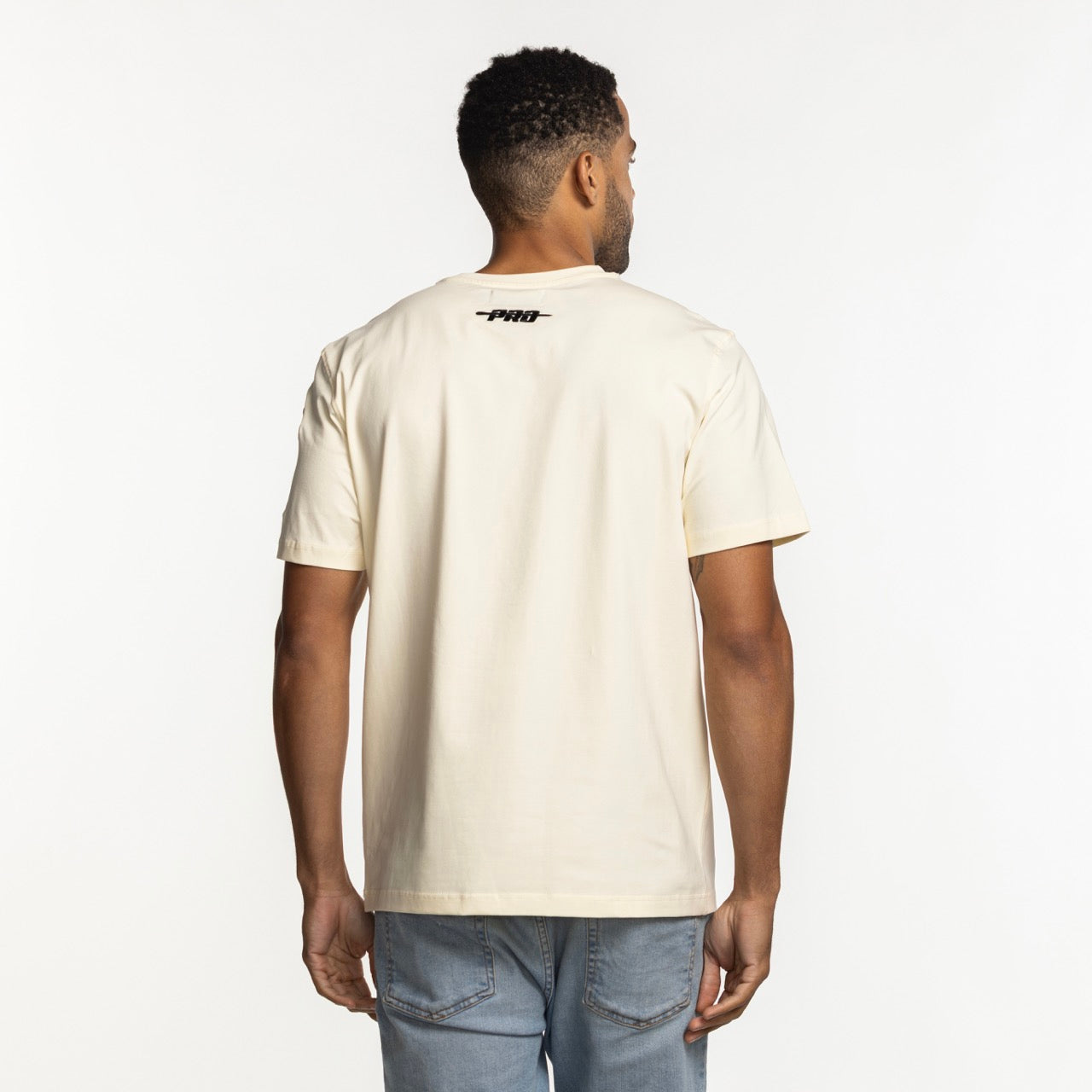 A man faces away, wearing the Pro Standard Miami HEAT Original Vice Nights Logo Tee—a cream, standard-fit cotton-spandex T-shirt with 