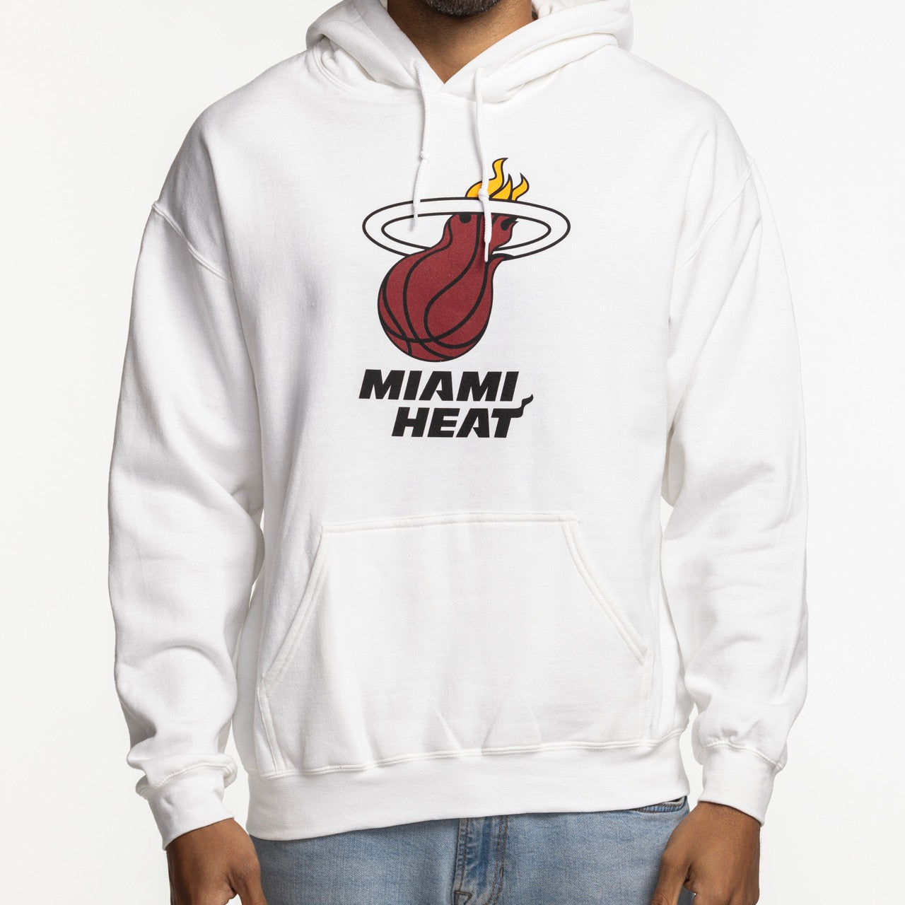 A person wears the Item Of The Game Miami HEAT Logo White Hoodie, featuring the team logo and name on the front, styled with light blue jeans. Made from a comfy cotton-poly blend; machine wash cold. Image cropped at neck.