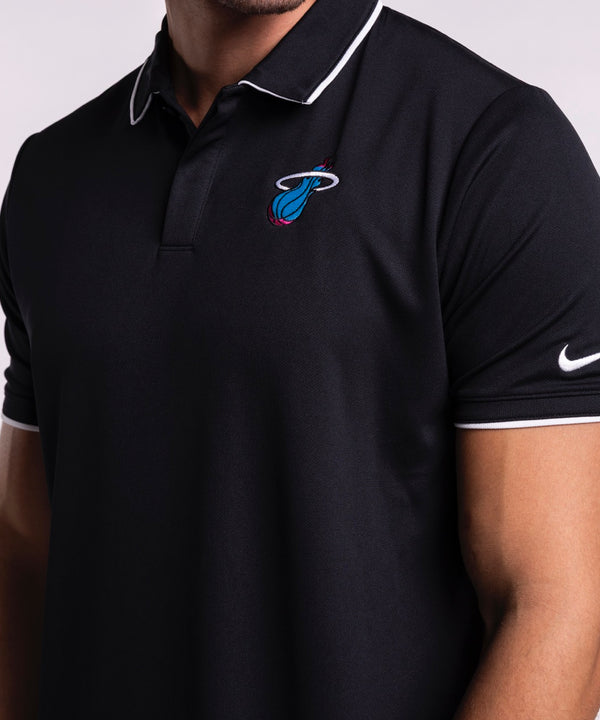 A man wearing a size L Nike Miami HEAT Original Vice Nights Logo Polo, with the Miami Heat logo and Nike swoosh on the sleeve, smiles and looks left against a plain light background.