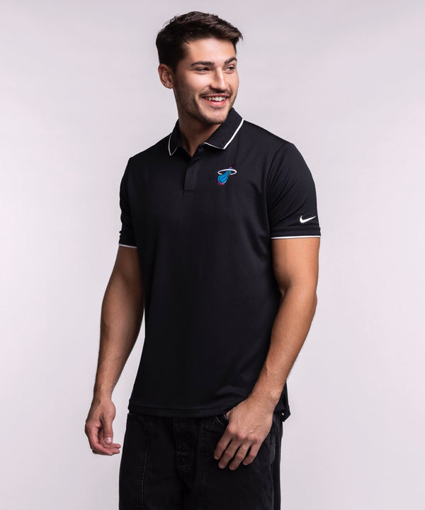 A man wearing a size L Nike Miami HEAT Original Vice Nights Logo Polo, with the Miami Heat logo and Nike swoosh on the sleeve, smiles and looks left against a plain light background.