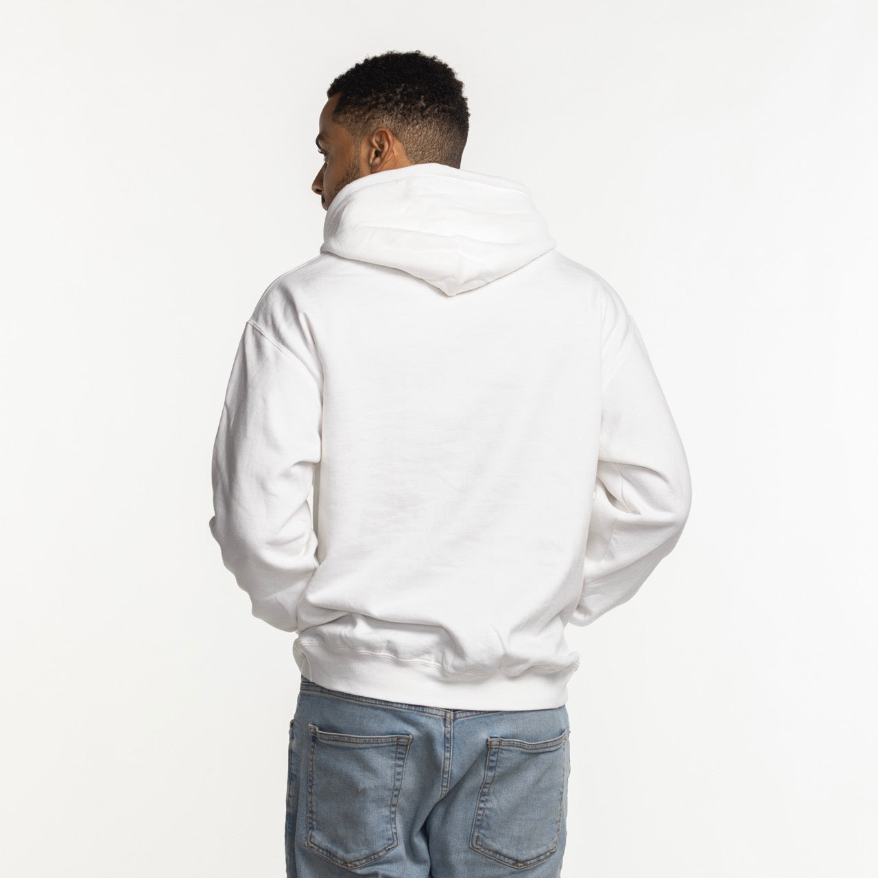 A person stands with their back to the camera, wearing an Item Of The Game Miami HEAT Logo White Hoodie in standard fit and light blue jeans. Made from a cotton-polyester blend, this hoodie is machine washable and set against a plain white background.