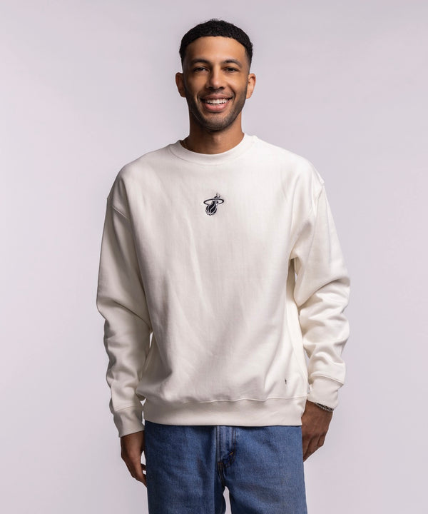 A man smiles against a light background, wearing the '47 Brand Miami HEAT Cream Logo Foundation Crewneck with a soft brushed interior and small embroidered logo on the chest, paired with blue jeans.